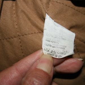 May include: A white fabric label with black text that reads "100% COTONE/COTTON LINING-FUTTER 70% RAYON/VISKOSE MADE IN ITALY".
