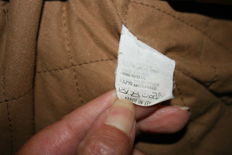 May include: A white fabric label with black text that reads "100% COTONE/COTTON LINING-FUTTER 70% RAYON/VISKOSE MADE IN ITALY".