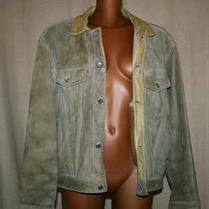 May include: A light brown suede jacket with a snap closure and a collar lined with a lighter brown suede. The jacket has two front pockets and a buttoned flap on each pocket.