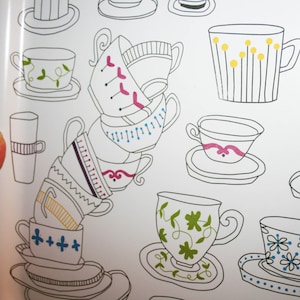 Könnte beinhalten: Ein Stapel von fünf Teetassen und Untertassen mit verschiedenen floralen und geometrischen Mustern. Die Tassen sind übereinander gestapelt, wobei die größte Tasse unten und die kleinste Tasse oben ist. Die Untertassen sind alle in verschiedenen Größen und Formen.
