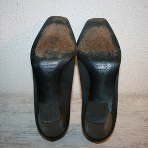 K&ouml;nnte beinhalten: Ein Paar schwarze Pumps mit einem Obermaterial aus strukturiertem Stoff. Die Sohlen sind aus Leder und tragen den Aufdruck "VERO CUOIO MADE IN ITALY 36".