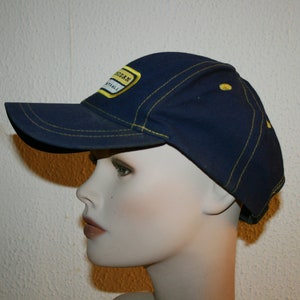 Pu&ograve; includere: Un cappello da baseball blu navy con un bordo cucito giallo e una toppa gialla che dice "Michigan Football".