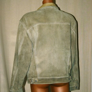 May include: A light brown suede jacket with a light brown collar and a button closure. The jacket has a distressed look and is made of a soft, comfortable material.