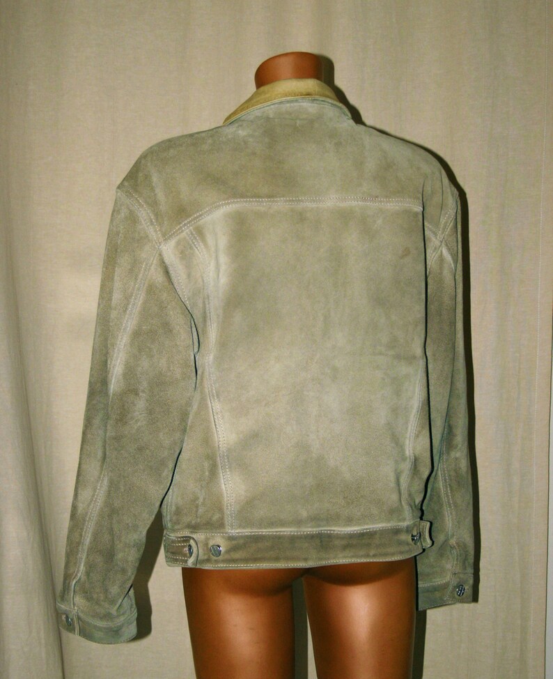 May include: A light brown suede jacket with a light brown collar and a button closure. The jacket has a distressed look and is made of a soft, comfortable material.