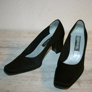 K&ouml;nnte beinhalten: Ein Paar schwarze Satin-Pumps mit quadratischer Spitze und Blockabsatz. Die Schuhe sind von der Marke "Diva" und wurden in Italien hergestellt.