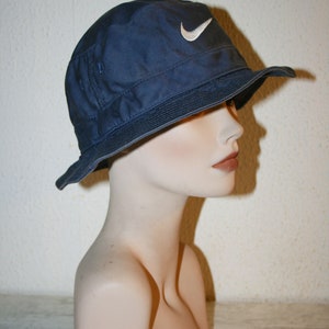 May include: A navy blue bucket hat with a white Nike swoosh logo.