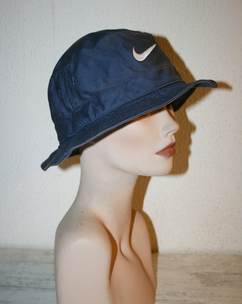 May include: A navy blue bucket hat with a white Nike swoosh logo.