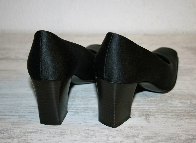 K&ouml;nnte beinhalten: Ein Paar schwarze Satin-Pumps mit Blockabsatz. Die Abs&auml;tze sind etwa 7,5 cm hoch.