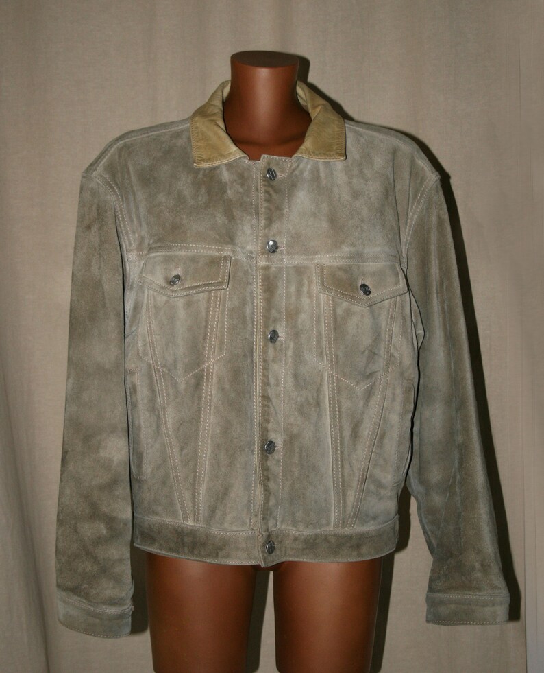 May include: A brown suede jacket with a tan corduroy collar and button closure. The jacket has two flap pockets on the chest and two angled pockets at the waist.