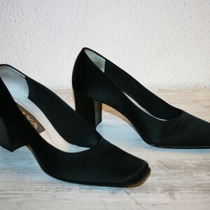 K&ouml;nnte beinhalten: Ein Paar schwarze Satin-Pumps mit quadratischer Spitze und Blockabsatz.