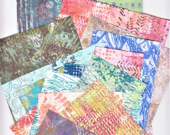 May include: A collection of colorful patterned paper scraps in various shades of blue, green, red, and yellow. The paper scraps are arranged in a fan shape, with the top scrap being a light orange with a swirling pattern.