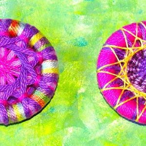 May include: Two colorful handmade buttons with a purple and pink center and a yellow and pink outer ring. The button on the left has a multi-colored outer ring, while the button on the right has a solid pink outer ring.