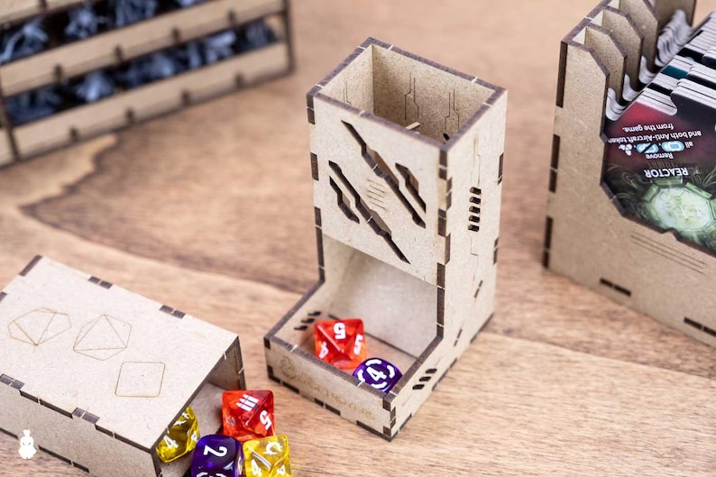 May include: A wooden dice tower with a cut-out design, holding red and purple dice. Other wooden boxes and dice are also visible, suggesting a tabletop gaming theme.