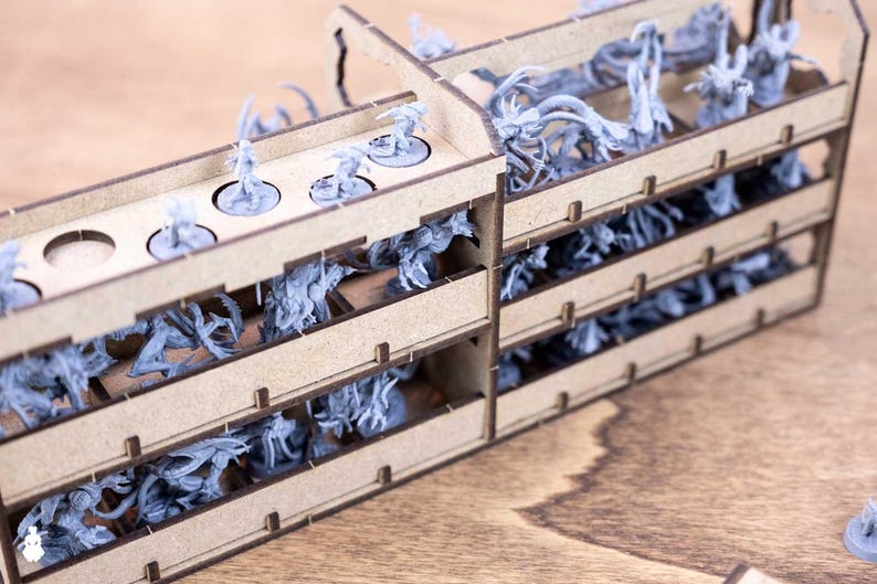 May include: A wooden organizer with multiple compartments filled with miniature figurines. The figurines are various shades of gray and are arranged in rows. The organizer has a natural wood finish and is designed for tabletop gaming.