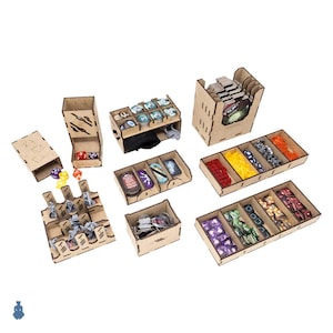 May include: A collection of laser-cut wooden game organizers. The organizers are designed to hold various game components, including cards, dice, and miniatures. The components are arranged in separate compartments, with a variety of colors visible.