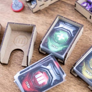 May include: Wooden card holders with stacks of game cards featuring health, ammo, and other item icons. The cards are labeled "ITEM" and are in various colors. Other wooden game pieces are also visible.