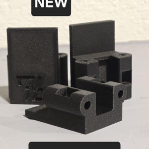 Peut inclure: Quatre pièces imprimées en 3D de couleur noire en fibre de carbone. Les pièces sont petites et ont une surface texturée. Le mot "NEW" est imprimé en blanc sur un rectangle noir dans la partie supérieure de l'image. Les mots "Carbon Fiber" sont imprimés en blanc sur un rectangle noir dans la partie inférieure de l'image.