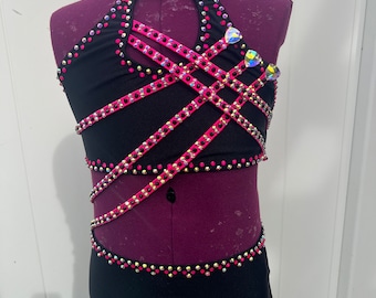 May include: A black dance costume with pink and silver embellishments. The costume features a halter top with criss-cross straps and a matching skirt.