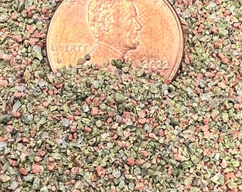 May include: A close-up of a 2022 US penny resting on a bed of small, colorful, and sparkly stones. The penny is in focus, while the stones are slightly blurred in the background.