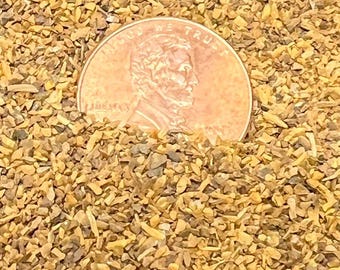 May include: A close-up of a pile of dried, chopped herbs. A US penny is placed on top of the herbs for scale.
