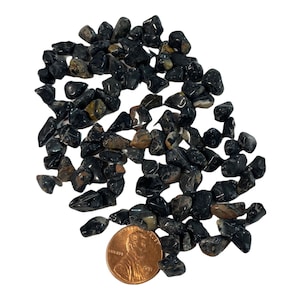 May include: A pile of black and brown tumbled stones, some with white streaks, with a US penny for scale.