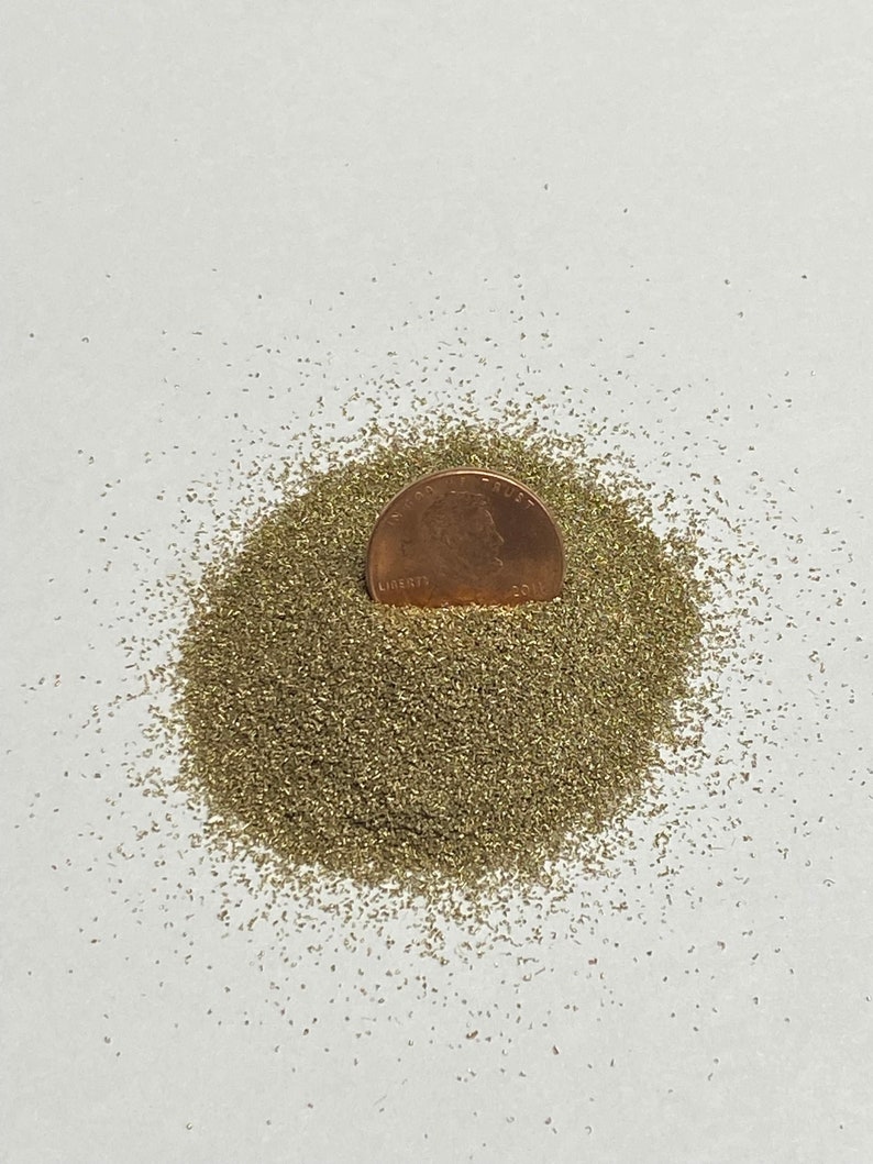 May include: A small pile of green glitter with a US penny on top for scale.
