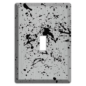 May include: A decorative light switch cover with a brushed metal finish. The cover is adorned with black paint splatters, creating a modern, abstract design. The switch opening is rectangular, and the cover has two screw holes.