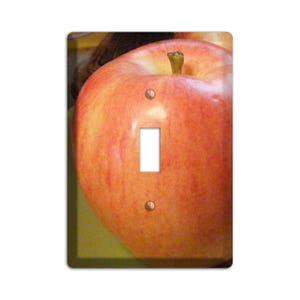May include: A red apple with a light pink blush, with a light brown stem and green leaf, is shown on a light green background. The apple is centered in the image and fills most of the frame. The image is a close-up of the apple, and the background is blurred.