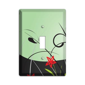 May include: A light green and black light switch cover with a stylized floral design featuring red flowers.