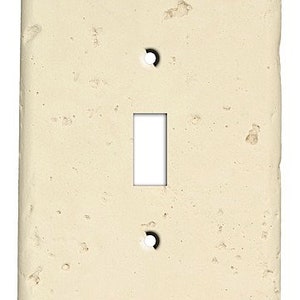 May include: A single-gang light switch plate with a textured, off-white finish. The plate has a rectangular shape with rounded corners.