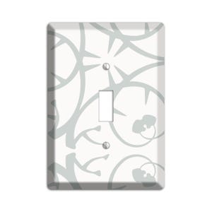 May include: A white light switch cover with a gray floral pattern.