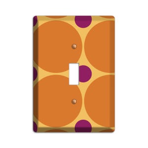May include: A light switch cover with a geometric pattern of orange and yellow circles with purple dots.