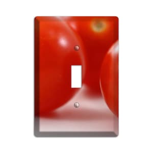May include: Close-up of three red tomatoes, with one tomato in the foreground and two tomatoes in the background.