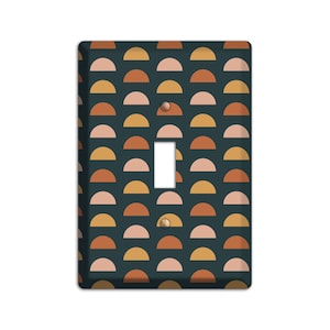 May include: A light switch cover with a geometric pattern of orange, yellow, and pink half circles on a dark blue background.