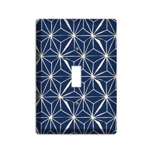 May include: A light switch cover with a geometric pattern in navy blue and white. The pattern is made up of repeating stars.