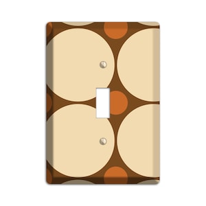 May include: A light switch cover with a brown background and a pattern of overlapping beige and orange circles.