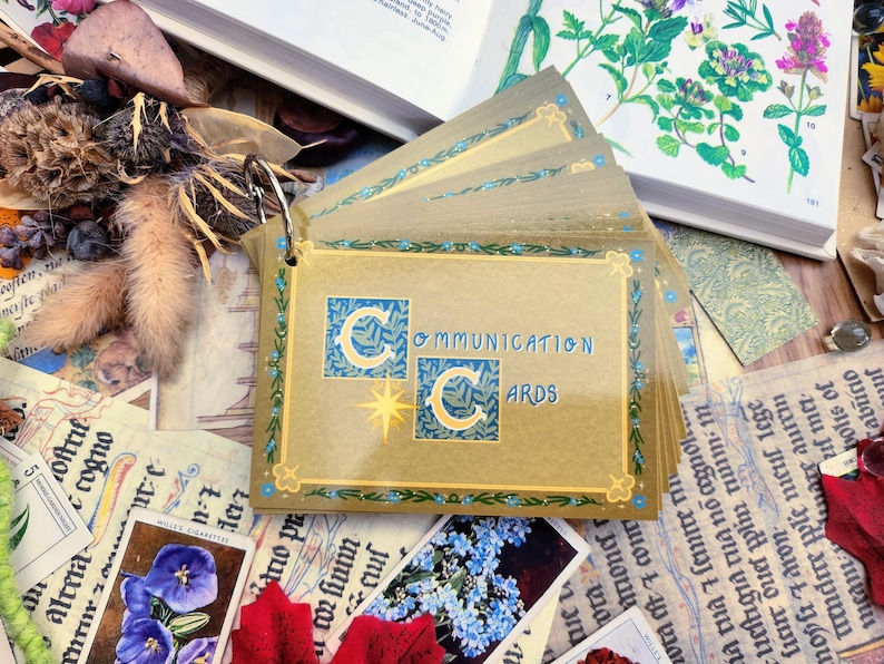 May include: A set of gold communication cards with a blue and gold design. The cards are labeled "Communication Cards" and feature a stylized "C" with a crescent moon and star design.