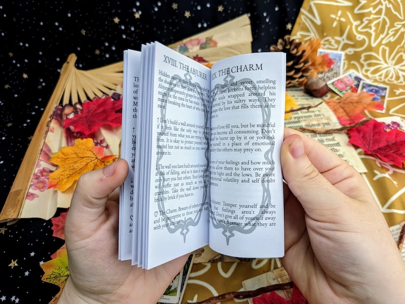 May include: Open book with black and white illustrations and text. The text reads "XVIII. The Abiure" and "The Charm". The book is open to a page with text about love and how to be mindful of your feelings.