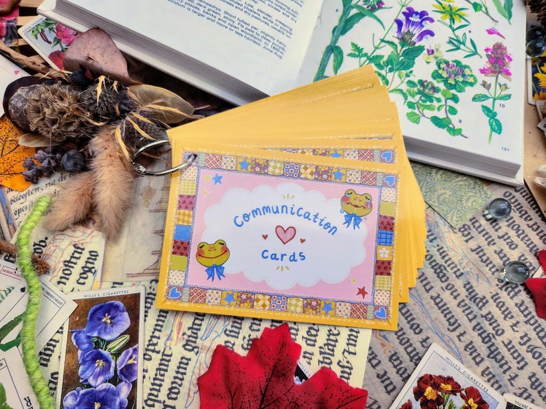 May include: A set of yellow communication cards with a pink and white design featuring a frog and the text "Communication Cards".