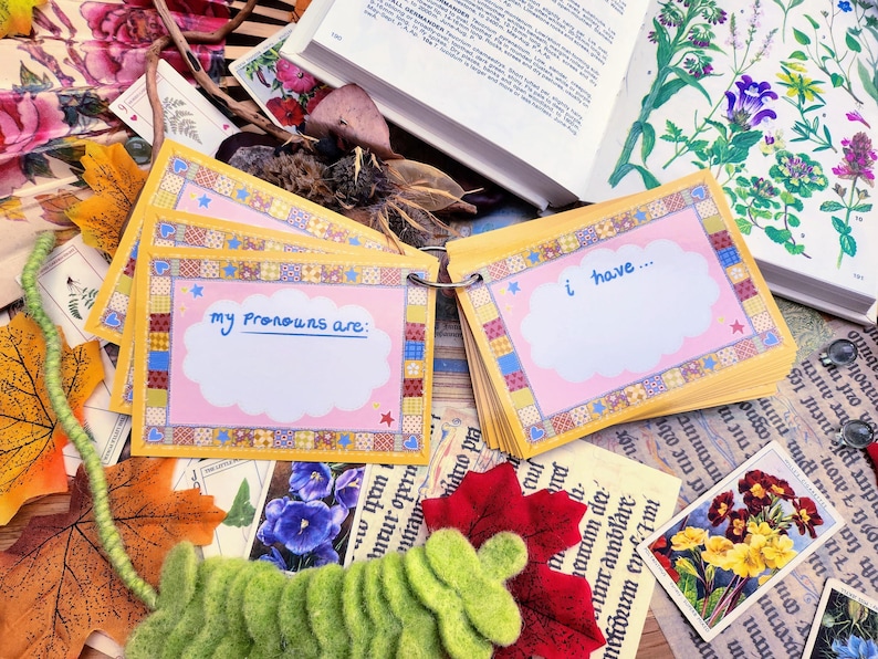 May include: A set of colorful cards with a pink and yellow patchwork design. The cards have a white cloud shape with the text "my pronouns are:" and "i have..." written in black marker.