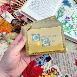 May include: A deck of Communication Cards with a gold background and blue accents. The cards feature a stylized crescent moon design and the text "Communication Cards".