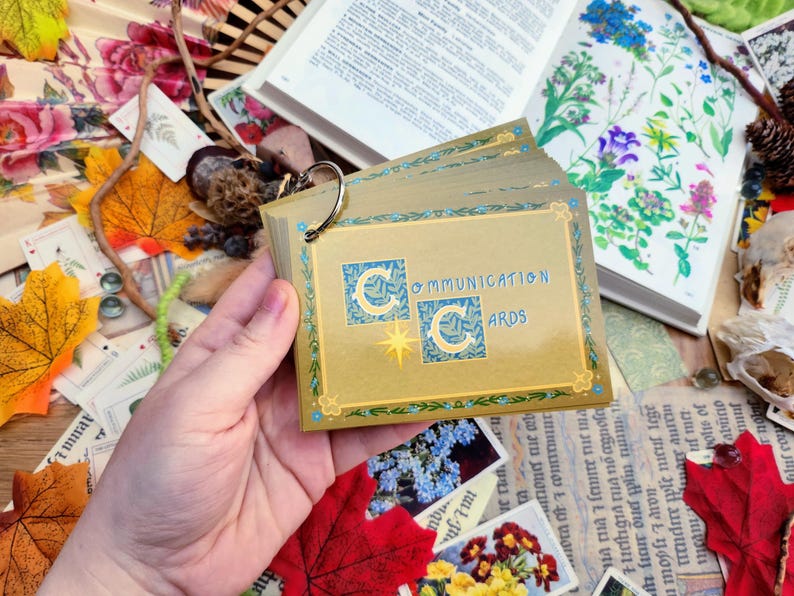 May include: A deck of Communication Cards with a gold background and blue accents. The cards feature a stylized crescent moon design and the text "Communication Cards".