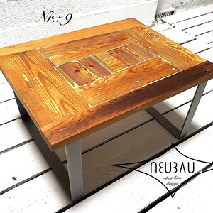 Könnte beinhalten: Ein quadratischer Couchtisch aus Holz mit natürlicher Maserung und einem geometrischen Design auf der Tischplatte. Er hat einen dunkelbraunen Rand und silberne Metallbeine. Der Text "Nr.: 9" ist sichtbar.