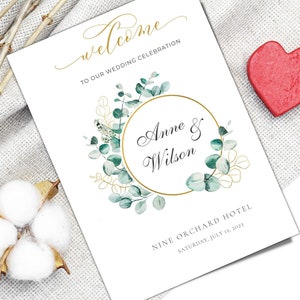 Puede incluir: Un programa de boda blanco con letras doradas que dice "welcome" y "TO OUR WEDDING CELEBRATION". El programa presenta un círculo dorado con los nombres "Anne & Wilson" y un diseño floral. La fecha es el 15 de julio de 2023.