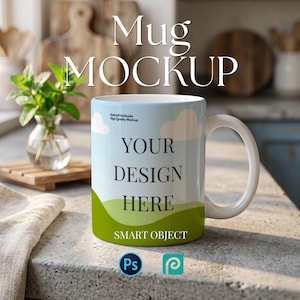May include: White ceramic mug mockup with a blue sky and green hill design. The mug has the text "YOUR DESIGN HERE" and "SMART OBJECT". The background includes a vase of mint and a wooden cutting board.