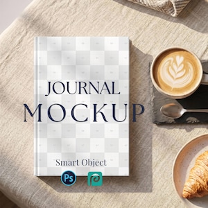 以下が含まれることがあります： ネイビーブルーの「JOURNAL MOCKUP」の文字が入ったジャーナルモックアップ。ベージュのリネンの上にジャーナルがあり、ラテアートのコーヒー、スプーン、クロワッサンが添えられています。