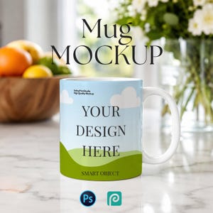 May include: A white ceramic mug with a blue sky and green hill design, with the words "YOUR DESIGN HERE" and "SMART OBJECT". The mug is in a mockup setting with the words "Mug MOCKUP" at the top.