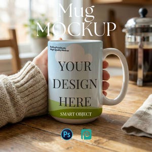 Op de afbeelding: Een witte keramische mok met een grote handgreep, vastgehouden door een persoon. De mok heeft een lucht- en grasontwerp met de tekst "YOUR DESIGN HERE" en "SMART OBJECT". De mok staat op een houten tafel.