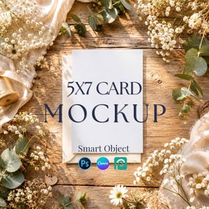 May include: A white 5x7 card mockup featuring the text 5X7 CARD MOCKUP and Smart Object, accompanied by three small circular icons for Photoshop, Canva, and a design program, displayed on a wooden surface with white flowers and greenery.