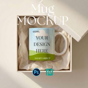 May include: A white ceramic mug with a handle, featuring a design with a blue sky, green grass, and the text "YOUR DESIGN HERE". The mug is presented inside a white box with crumpled paper. The words "Mug MOCKUP" are at the top.